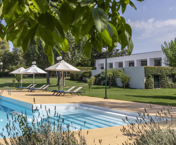 Amalia Hotel Olympia pool with sunbeds and umbrellas and a garden